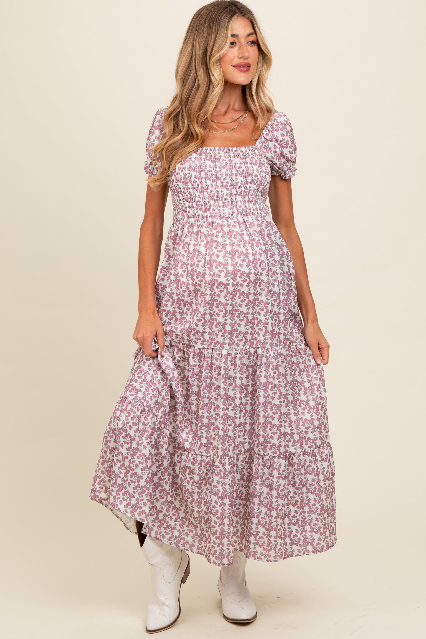 Woman wearing a floral dress with white boots on a beige background