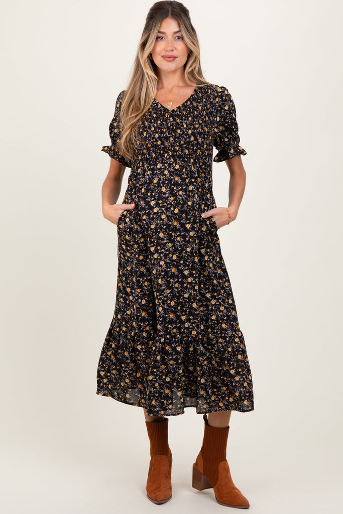 Woman wearing a black floral dress with brown boots on a white background