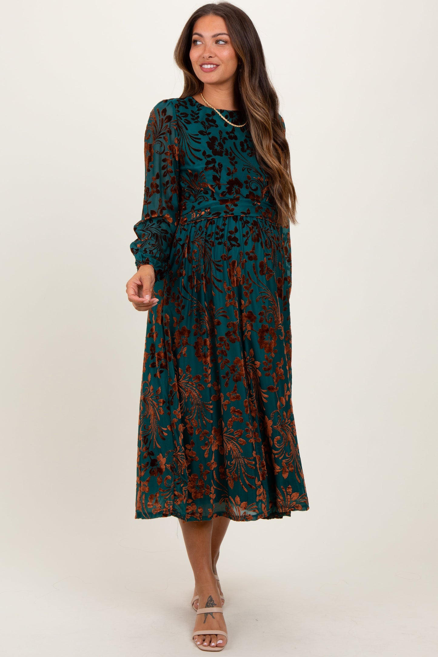 Woman wearing a long-sleeve, patterned dress against a white background