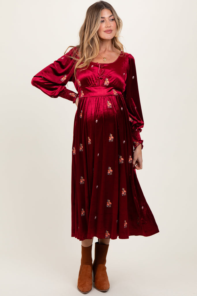 Woman wearing a burgundy dress with floral patterns on a white background