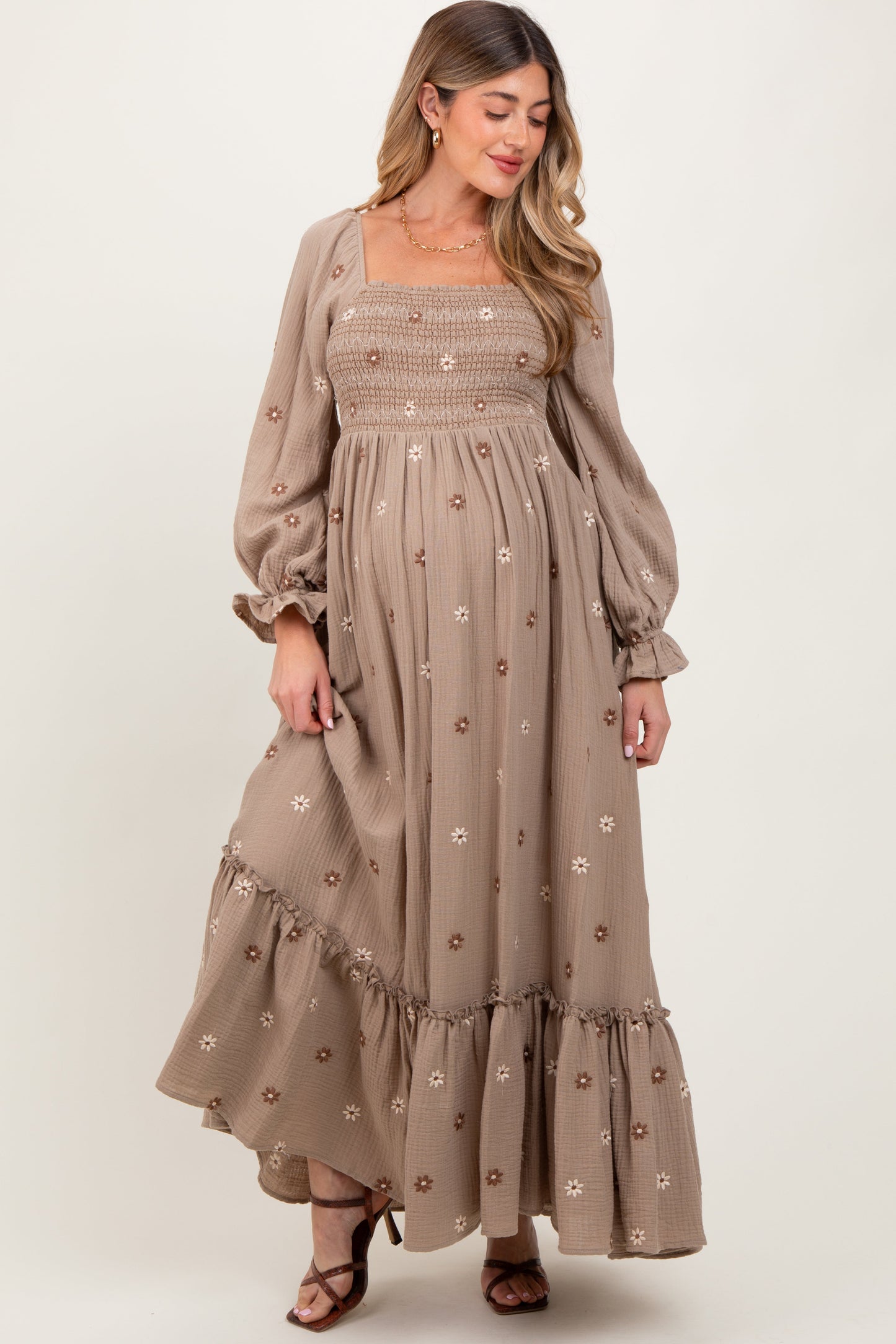 Woman wearing a long, embroidered dress with puff sleeves on a white background