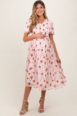 Woman wearing a white dress with red floral pattern on a plain background