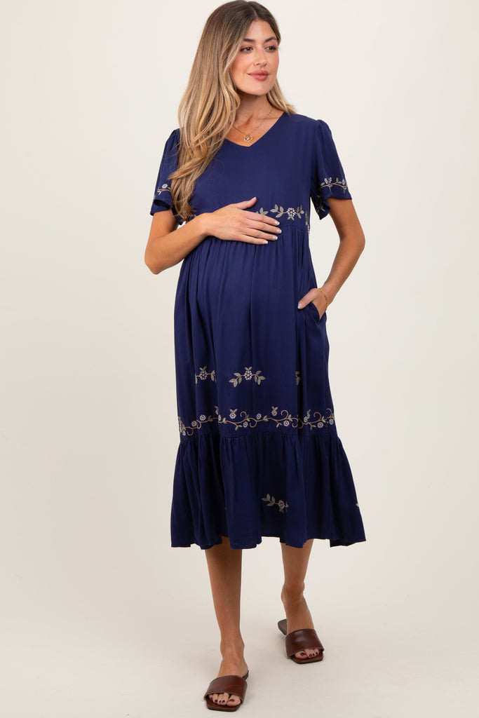 Woman wearing a blue dress with floral embroidery on a white background