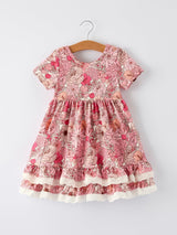 Pink floral dress on a hanger against a white background