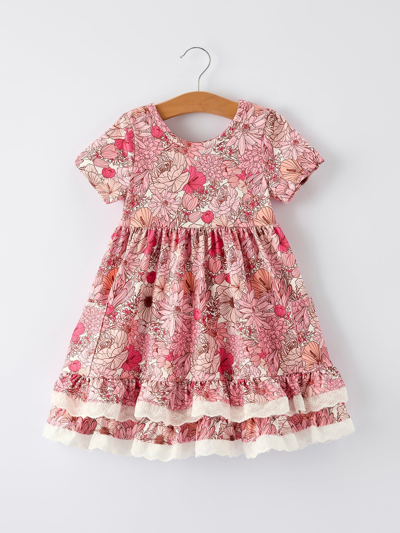 Pink floral dress on a hanger against a white background