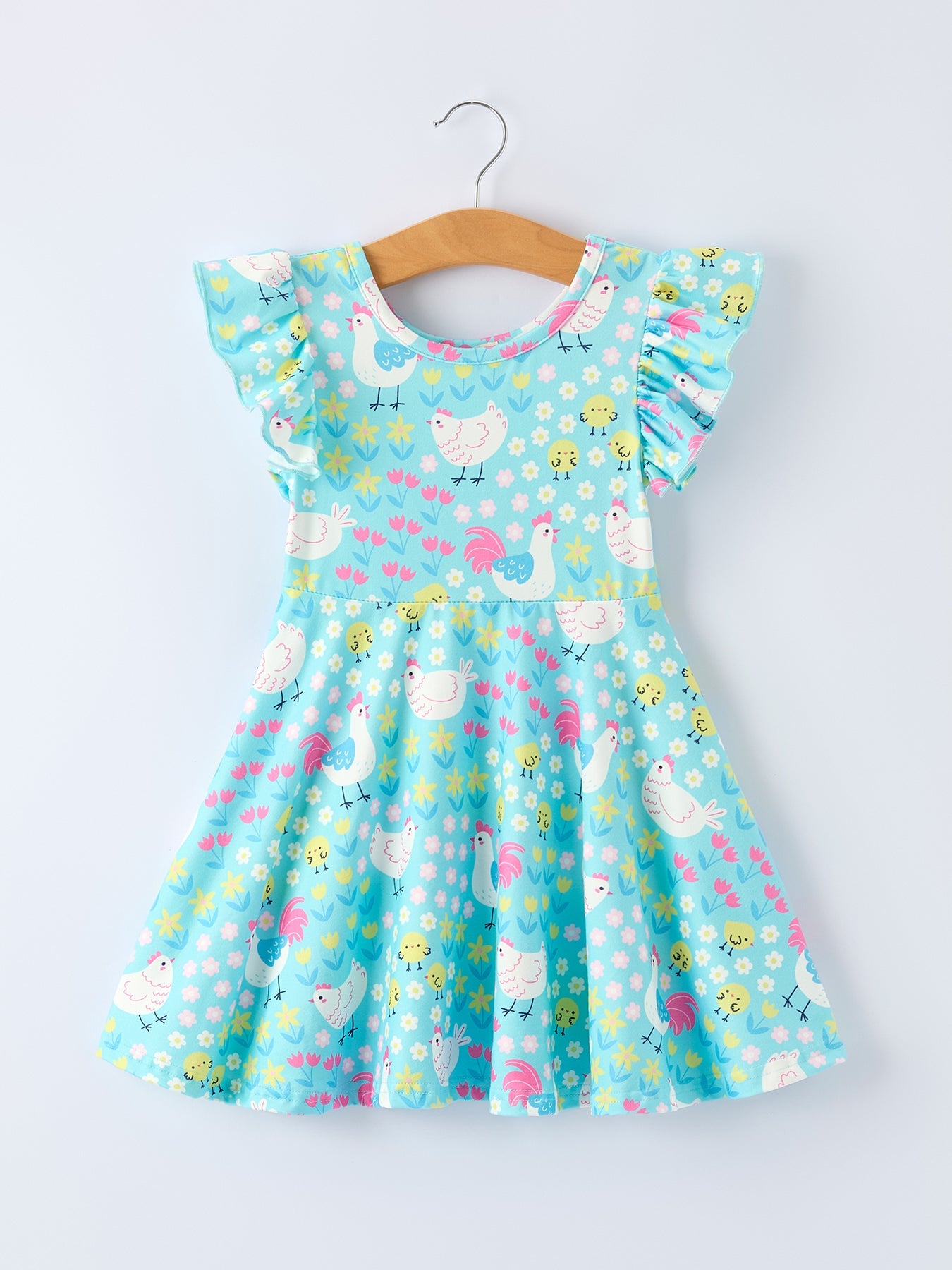 Children's dress with chicken pattern on a hanger against a white background