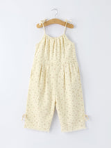 Yellow floral jumpsuit hanging on a wooden hanger against a white background