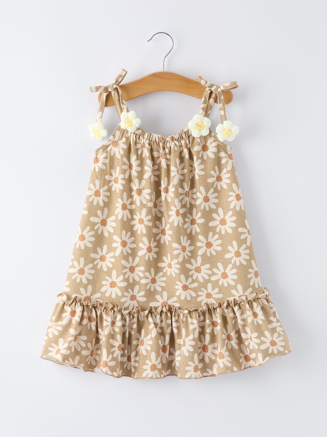 Beige dress with floral pattern on a hanger against a white background