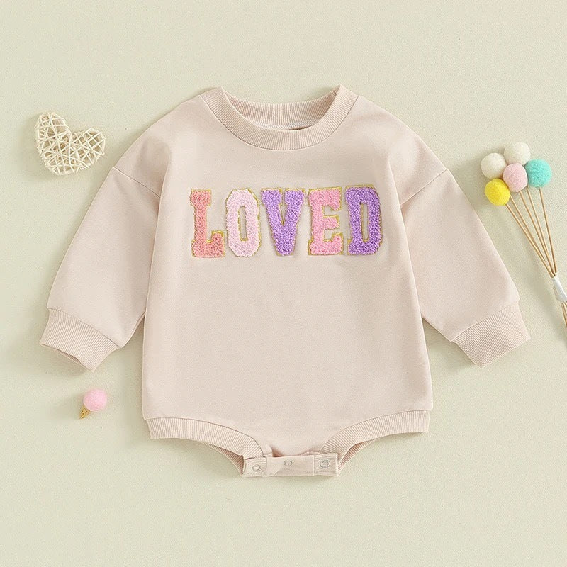 Baby romper with 'LOVED' text on a light green background