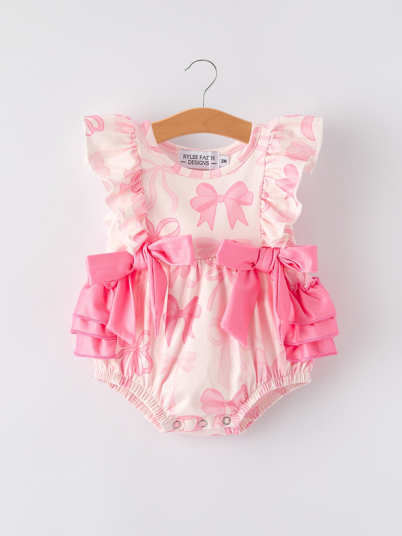 Pink baby romper with ruffles and bows on a white background