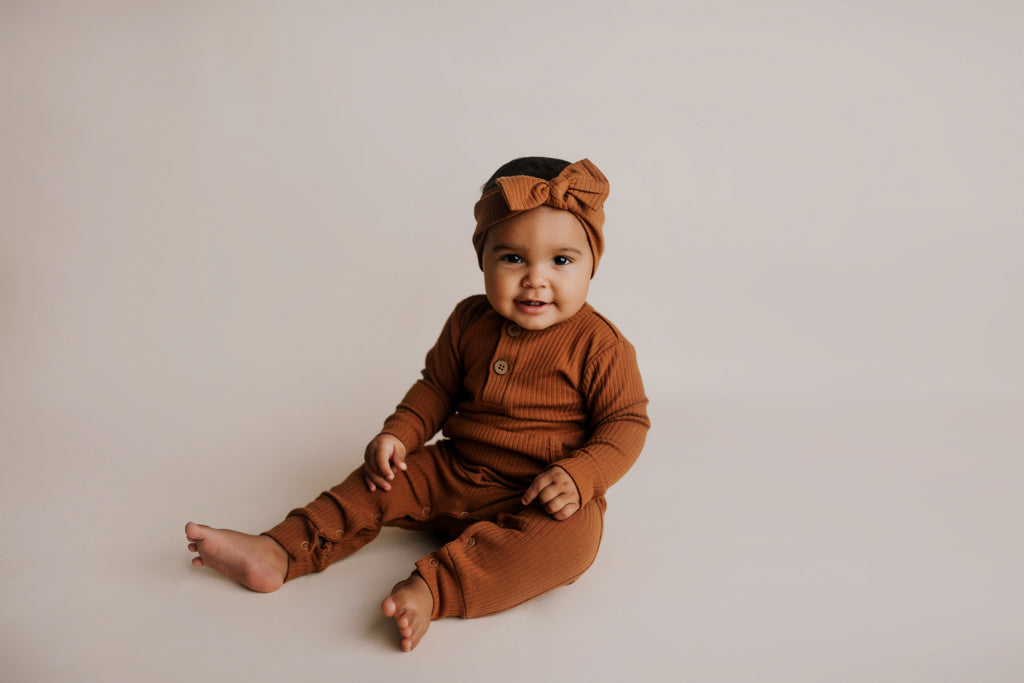 Organic cotton ribbed onesie with front buttons and leg snaps, ideal for comfort and style during any activity.
