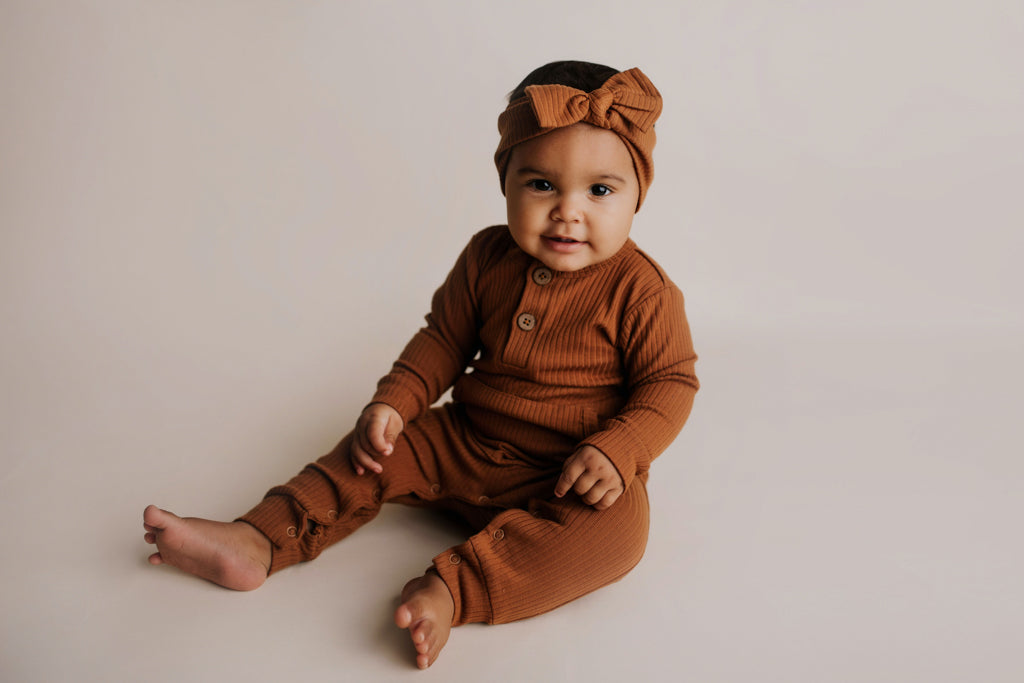 Organic cotton ribbed onesie with front buttons and leg snaps, ideal for comfort and style during any activity.
