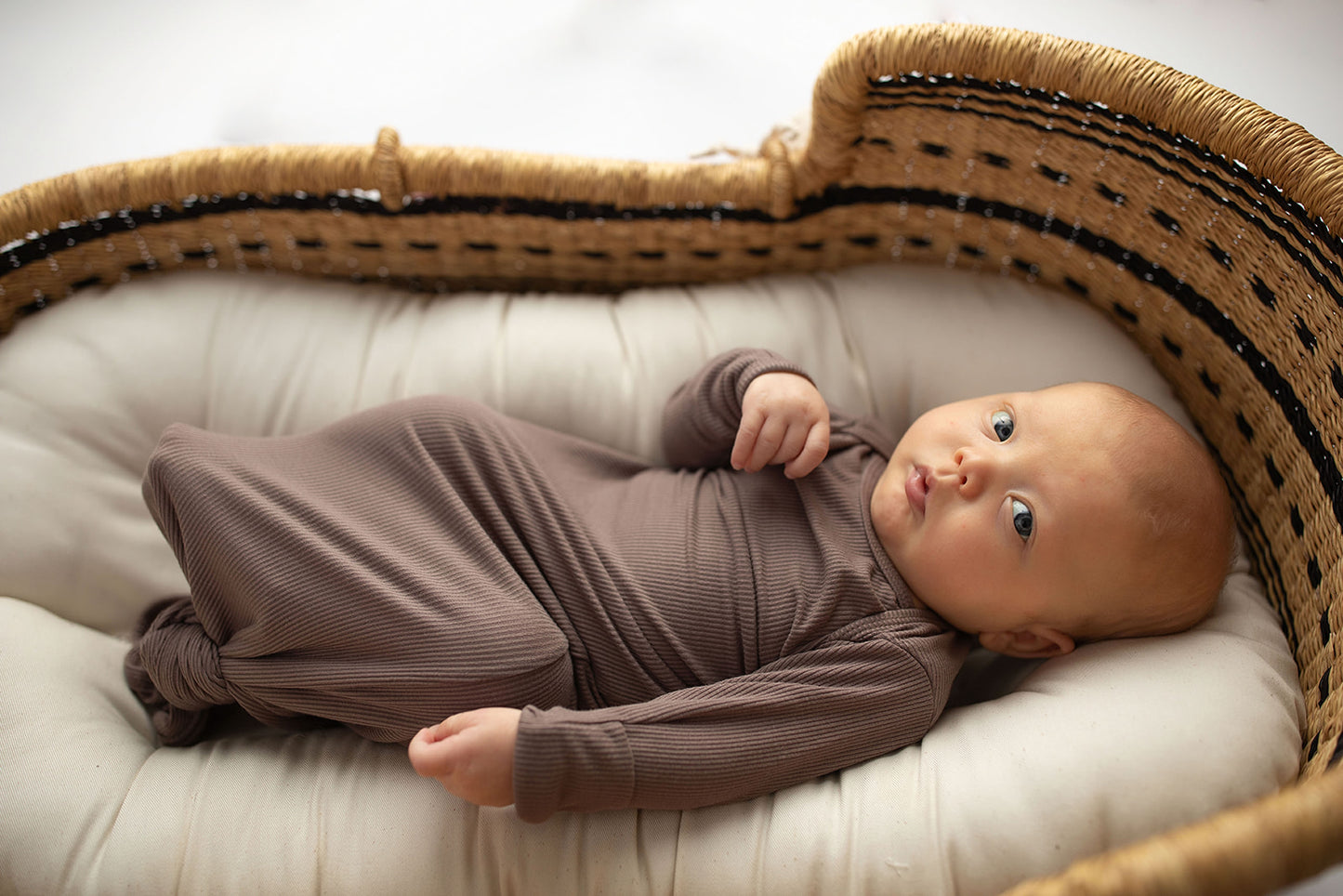 Ultra-soft, stretchy gender neutral baby gowns designed for comfort, featuring tie bottom and pull-down shoulder tabs for convenience. Cocoa Knotted Gown in a Snuggle Me Organics in a Plum + Sparrow Moses Baby Basket