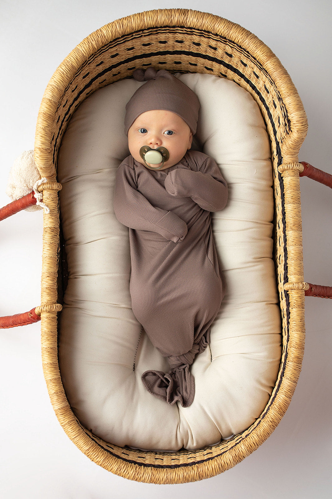 Ultra-soft, stretchy gender neutral baby gowns designed for comfort, featuring tie bottom and pull-down shoulder tabs for convenience. Cocoa Knotted Gown in a Snuggle Me Organics in a Plum + Sparrow Moses Baby Basket