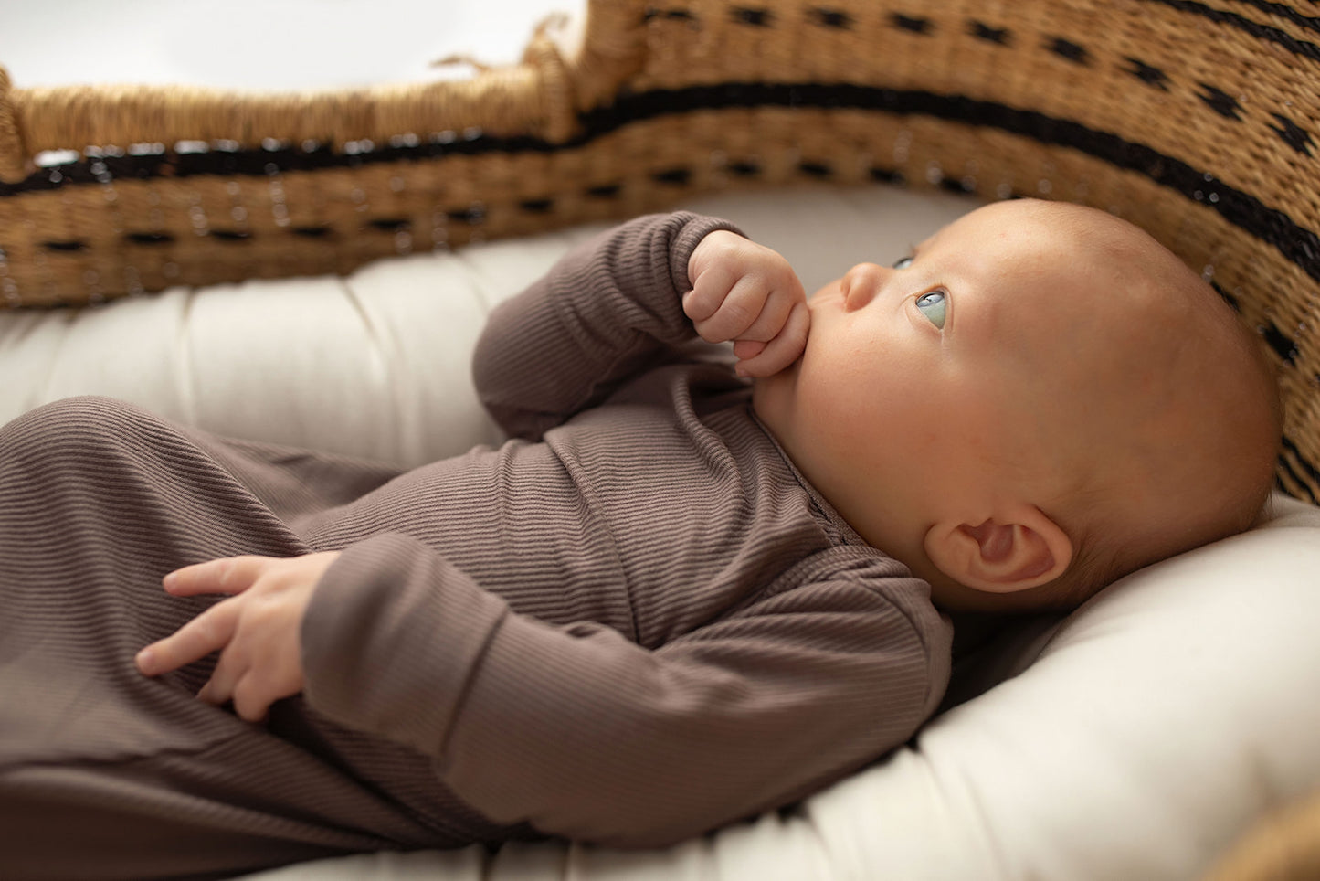 Ultra-soft, stretchy gender neutral baby gowns designed for comfort, featuring tie bottom and pull-down shoulder tabs for convenience. Cocoa Knotted Gown in a Snuggle Me Organics in a Plum + Sparrow Moses Baby Basket