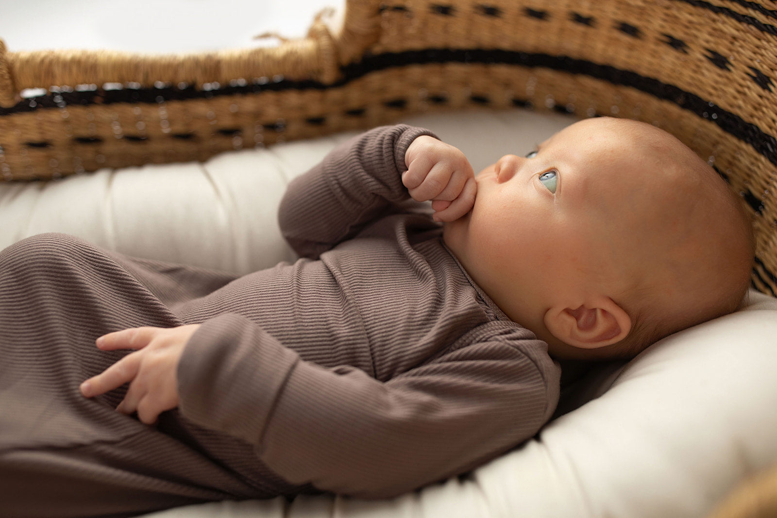 Ultra-soft, stretchy gender neutral baby gowns designed for comfort, featuring tie bottom and pull-down shoulder tabs for convenience. Cocoa Knotted Gown in a Snuggle Me Organics in a Plum + Sparrow Moses Baby Basket