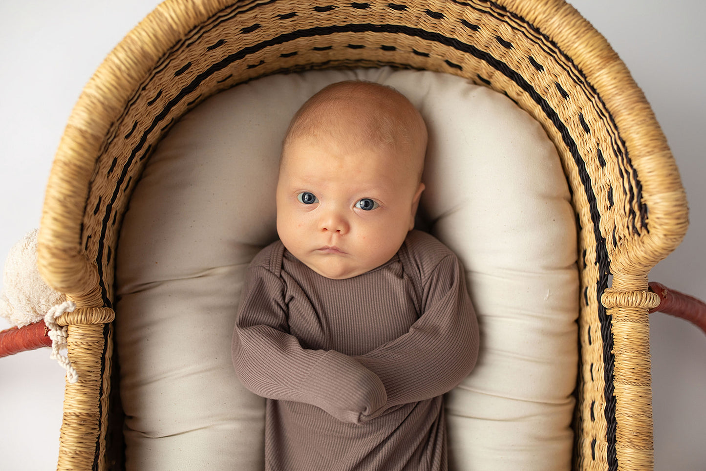 Ultra-soft, stretchy gender neutral baby gowns designed for comfort, featuring tie bottom and pull-down shoulder tabs for convenience. Cocoa Knotted Gown in a Snuggle Me Organics in a Plum + Sparrow Moses Baby Basket