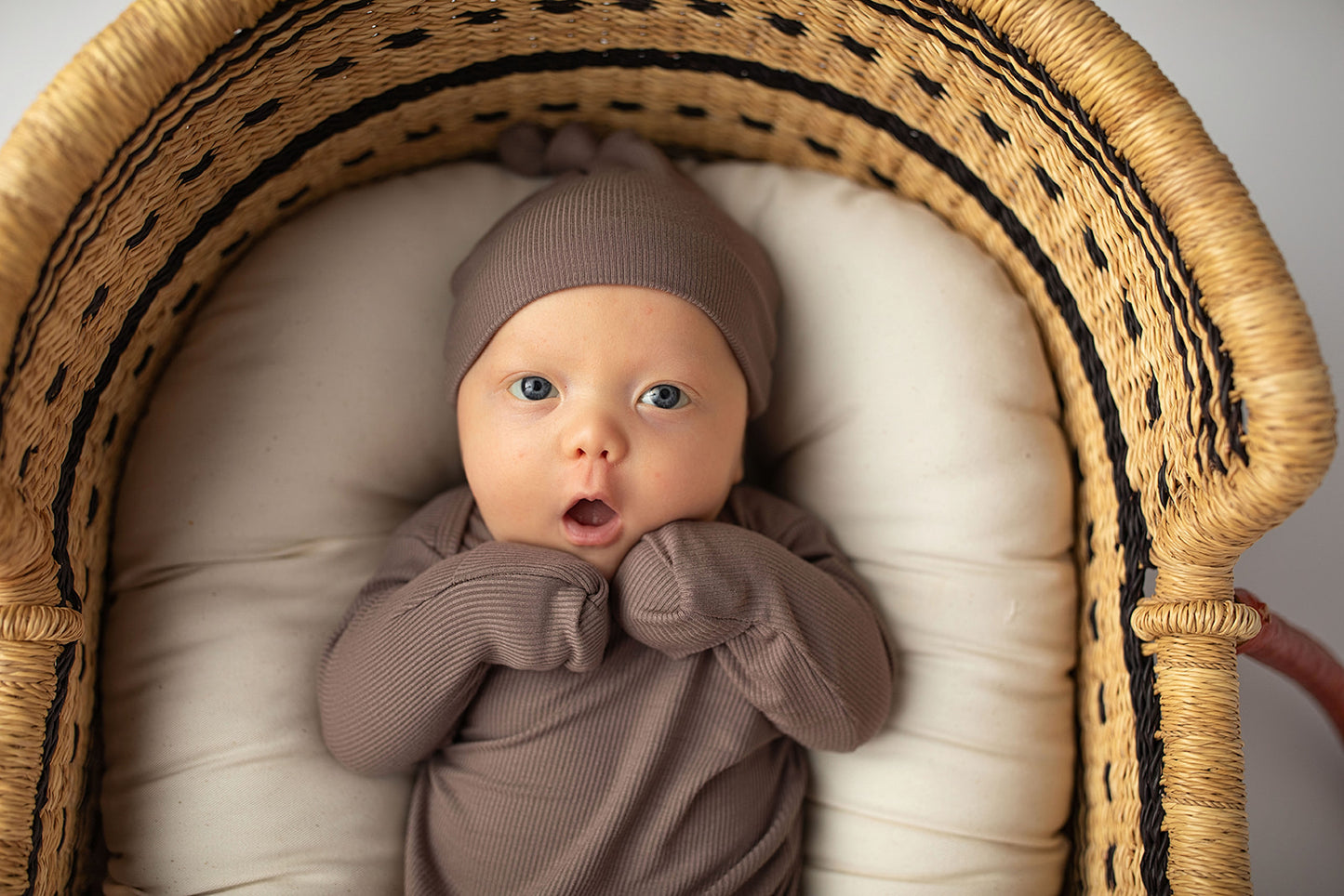Ultra-soft, stretchy gender neutral baby gowns designed for comfort, featuring tie bottom and pull-down shoulder tabs for convenience. Cocoa Knotted Gown in a Snuggle Me Organics in a Plum + Sparrow Moses Baby Basket
