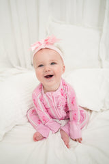 Baby wearing a pink outfit with a bow on a white background