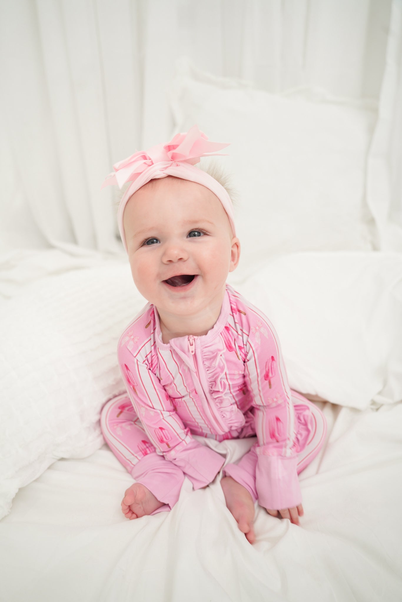 Baby wearing a pink outfit with a bow on a white background