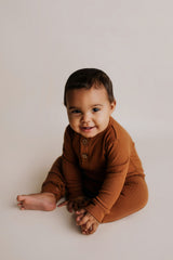 Organic cotton ribbed onesie with front buttons and leg snaps, ideal for comfort and style during any activity.