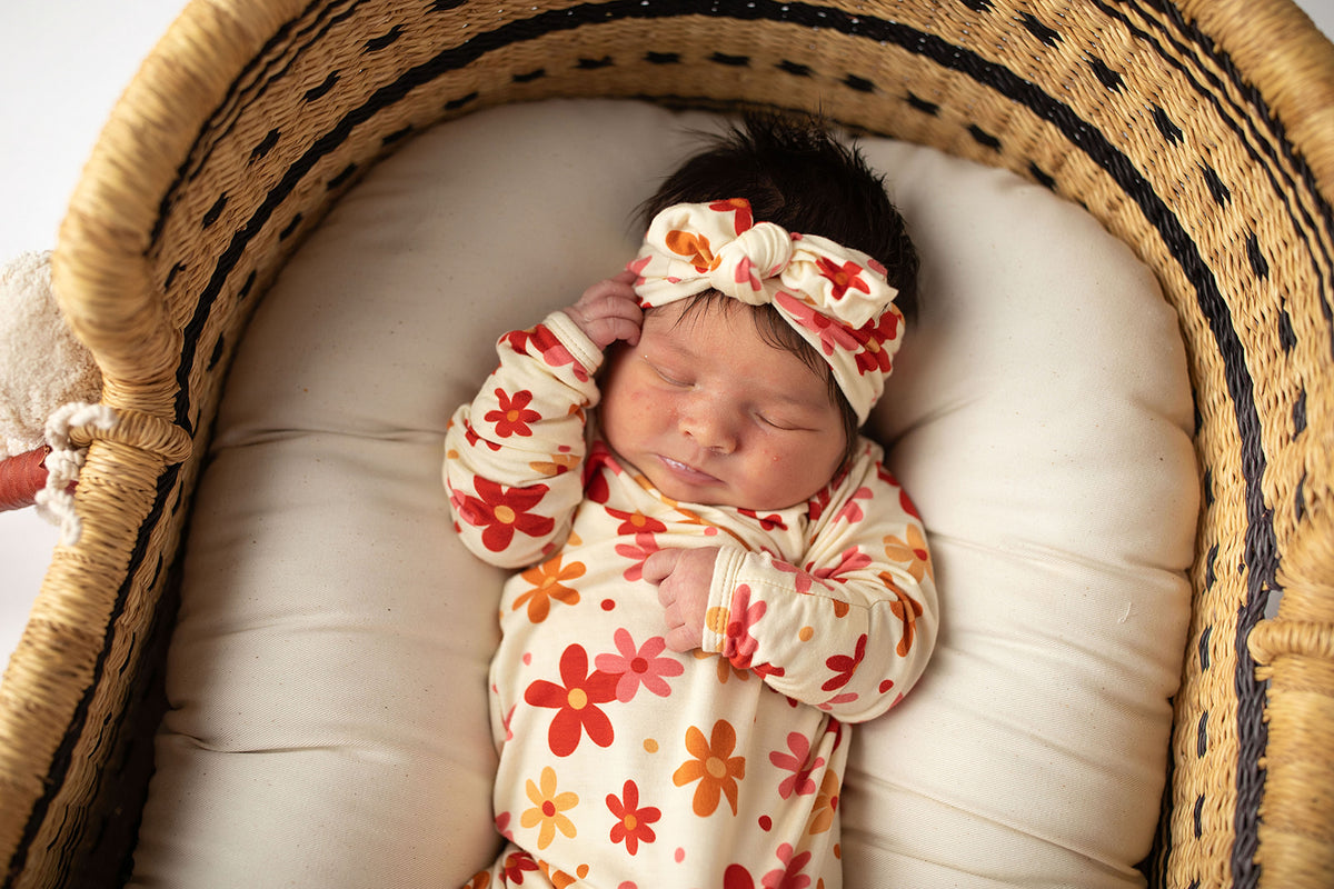 Three Little Tots Flower 70s knotted newborn baby gown is ultra soft and the perfect gift for a newborn baby. Shown in a Snuggle Me Organic in a Plum + Sparrow Moses Basket