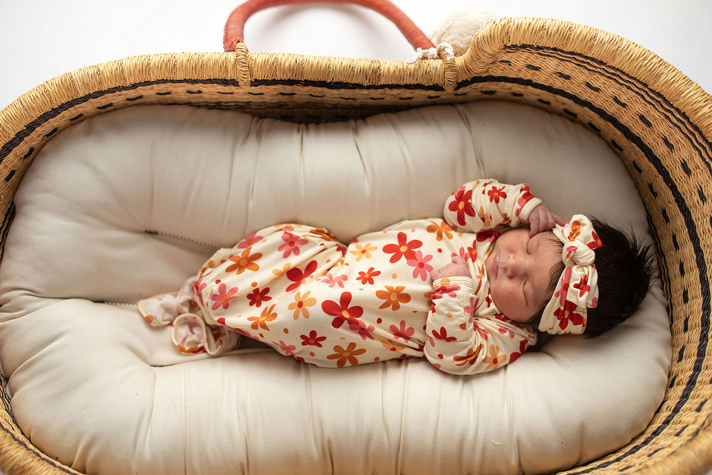 Three Little Tots Flower 70s knotted newborn baby gown is ultra soft and the perfect gift for a newborn baby. Shown in a Snuggle Me Organic in a Plum + Sparrow Moses Basket