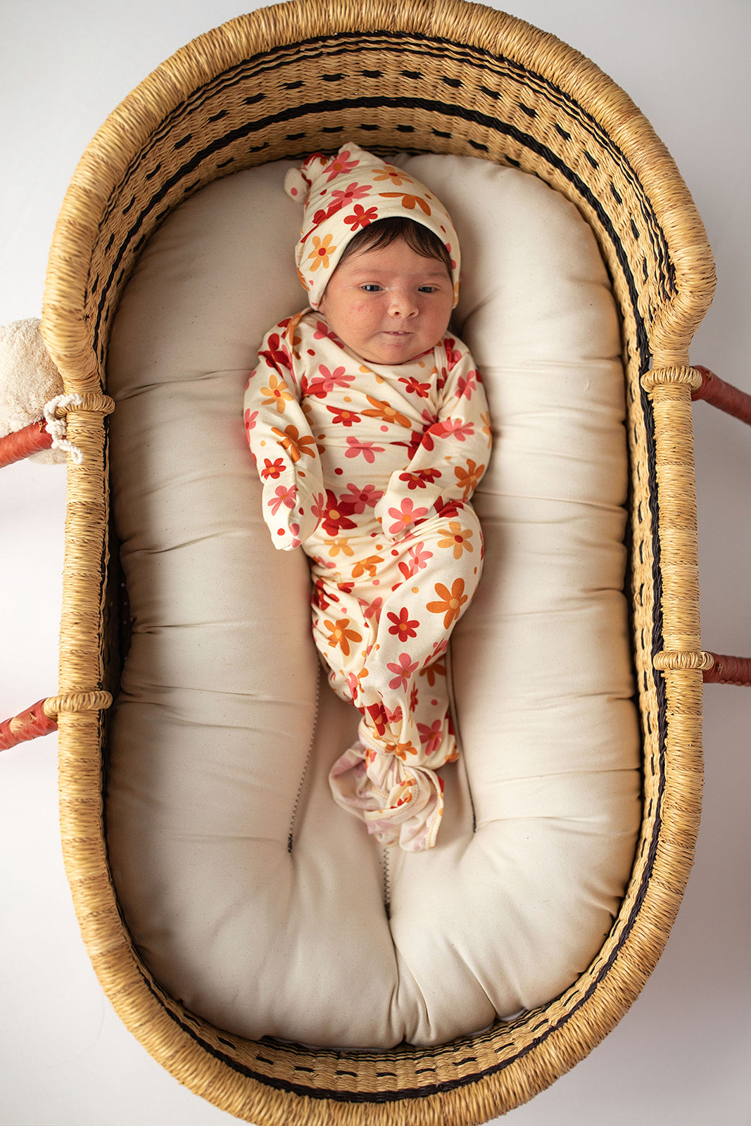 Three Little Tots Flower 70s knotted newborn baby gown is ultra soft and the perfect gift for a newborn baby. Shown in a Snuggle Me Organic in a Plum + Sparrow Moses Basket