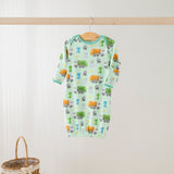 Baby onesie with vehicle pattern hanging on a wooden rod against a white wall.