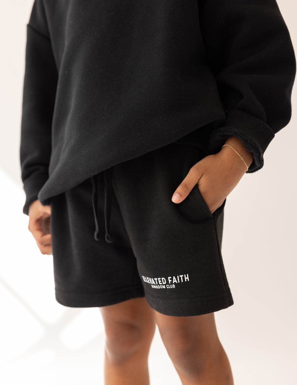 Person wearing black shorts with 'Elevated Faith' branding on a white background