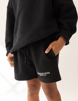 Person wearing black shorts with 'Elevated Faith' branding on a white background
