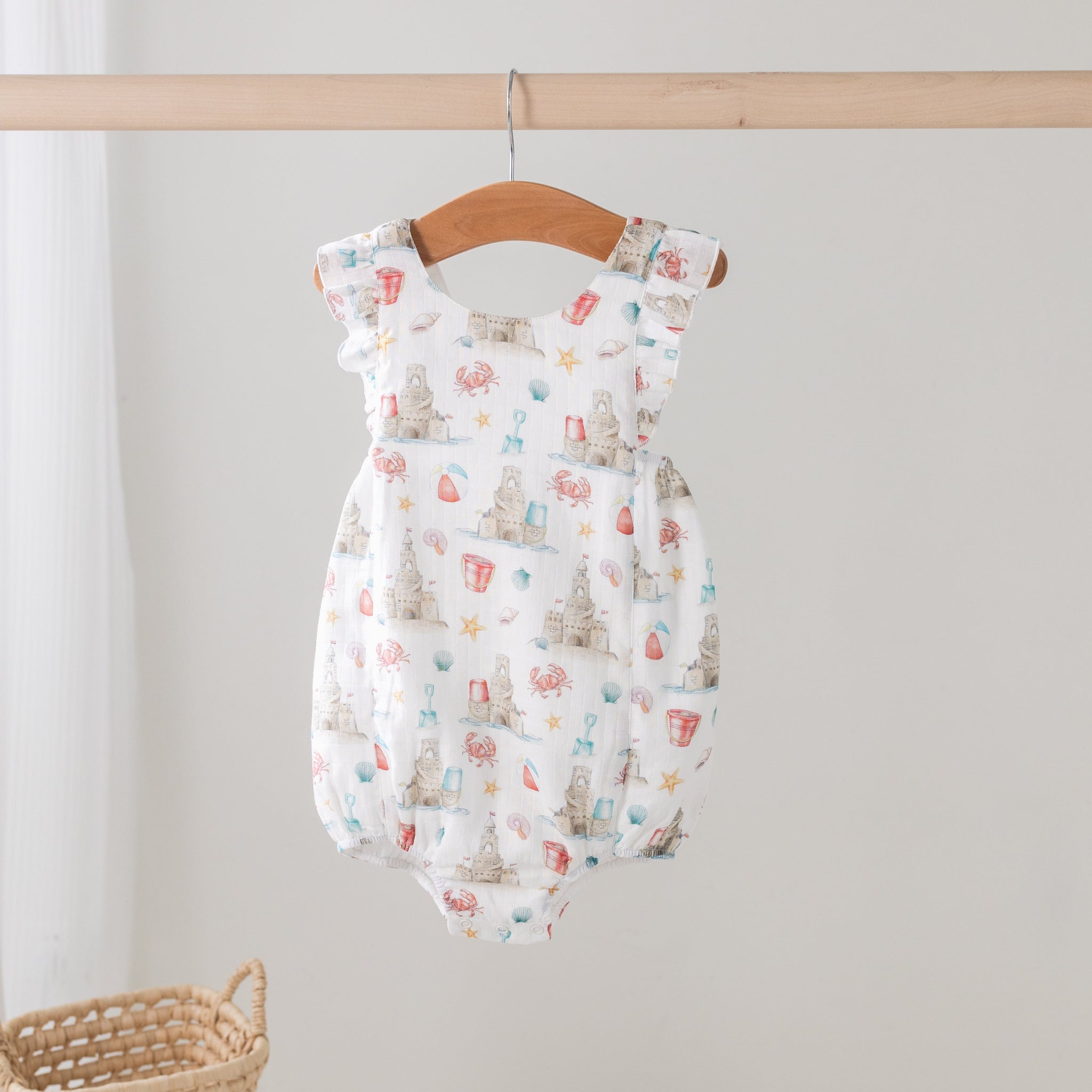 Baby romper with colorful pattern on a wooden hanger against a white background