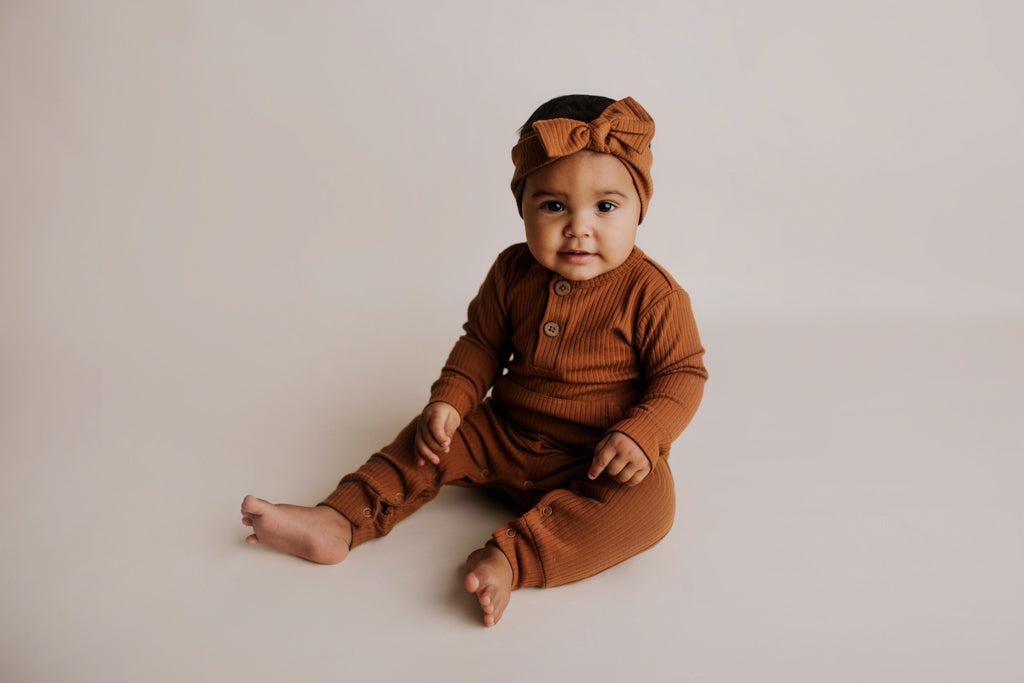 Organic cotton ribbed onesie with front buttons and leg snaps, ideal for comfort and style during any activity.