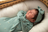Three Little Tots Arrow Newborn Knotted Baby Gown. Ultra Soft baby gown. Little newborn girl with lots of hair in a Snuggle Me organic in a Plum and Sparrow Moses Basket. 