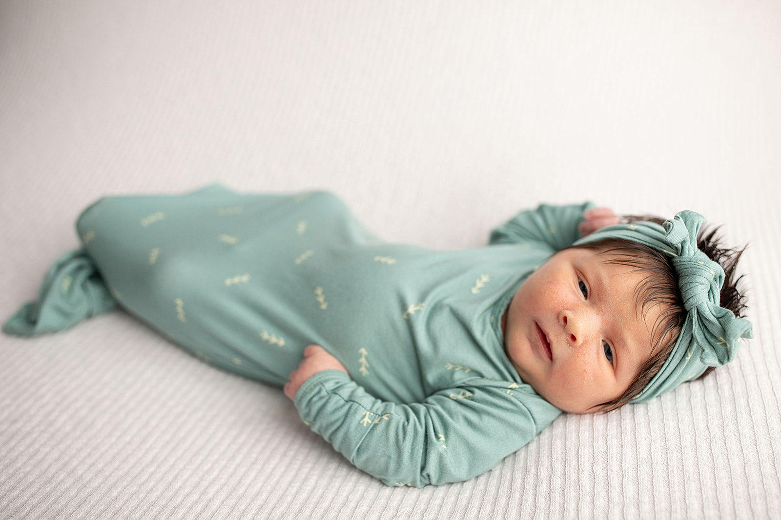 Three Little Tots Arrow Newborn Knotted Baby Gown with bow. Newborn baby girl with a lot of hair.