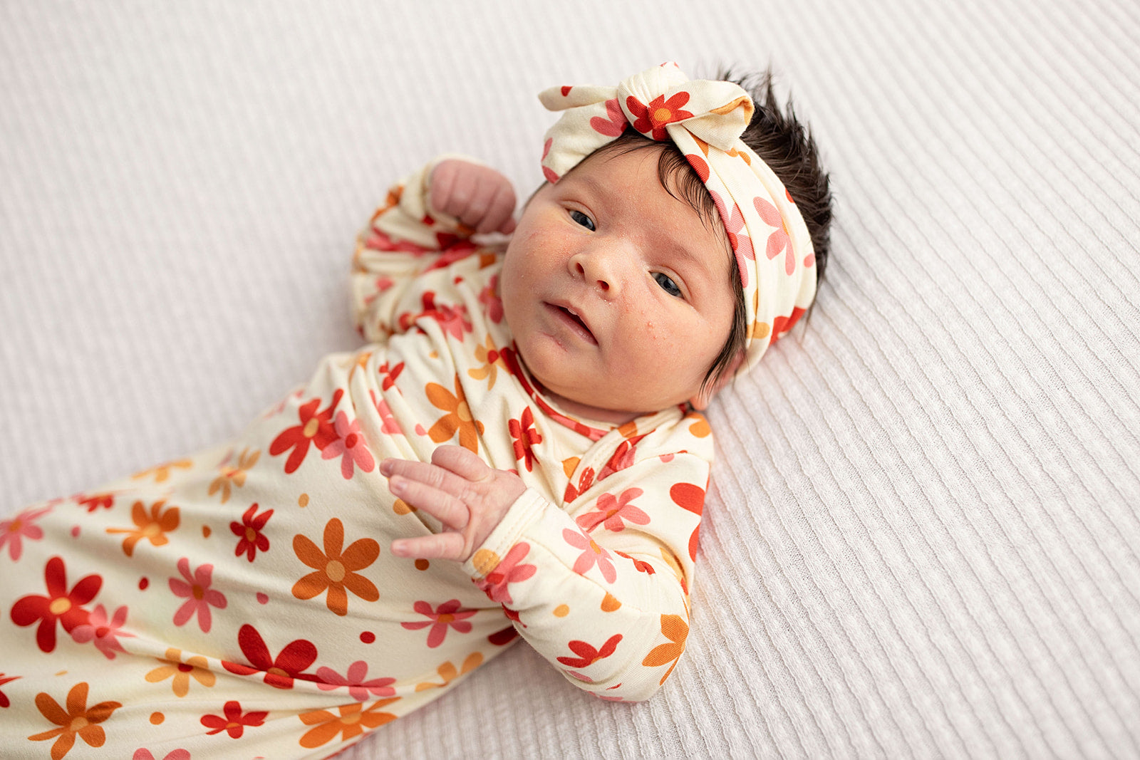 Three Little Tots Flower 70s knotted newborn baby gown is ultra soft and the perfect gift for a newborn baby. Shown in a Snuggle Me Organic in a Plum + Sparrow Moses Basket