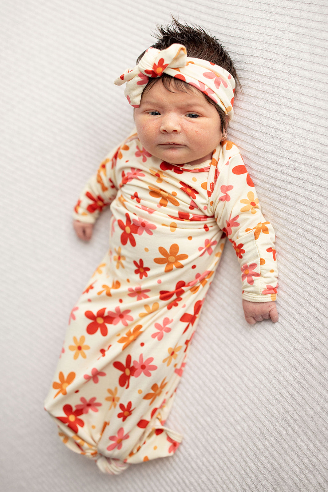 Three Little Tots Flower 70s knotted newborn baby gown is ultra soft and the perfect gift for a newborn baby. Shown in a Snuggle Me Organic in a Plum + Sparrow Moses Basket