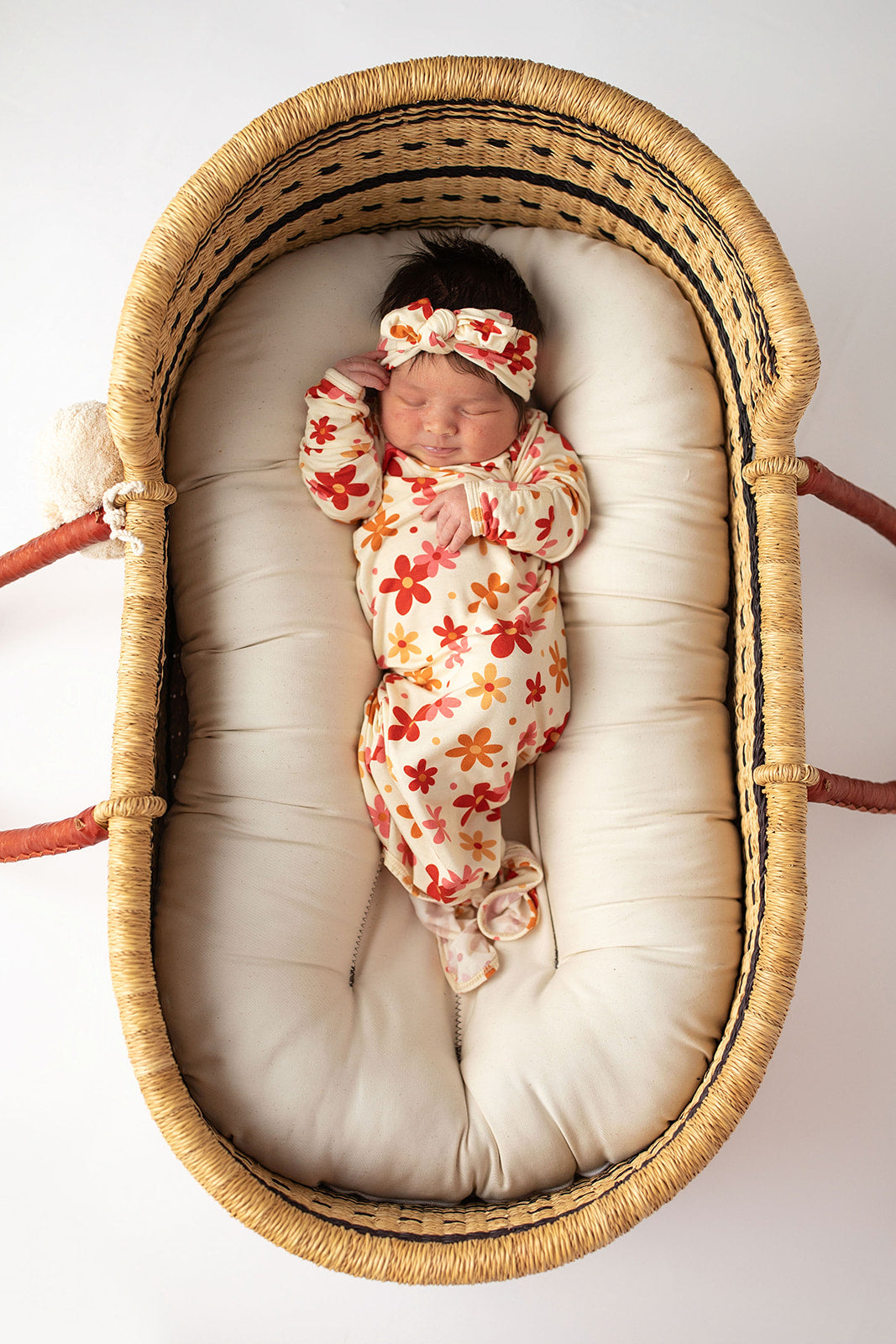 Three Little Tots Flower 70s knotted newborn baby gown is ultra soft and the perfect gift for a newborn baby. Shown in a Snuggle Me Organic in a Plum + Sparrow Moses Basket