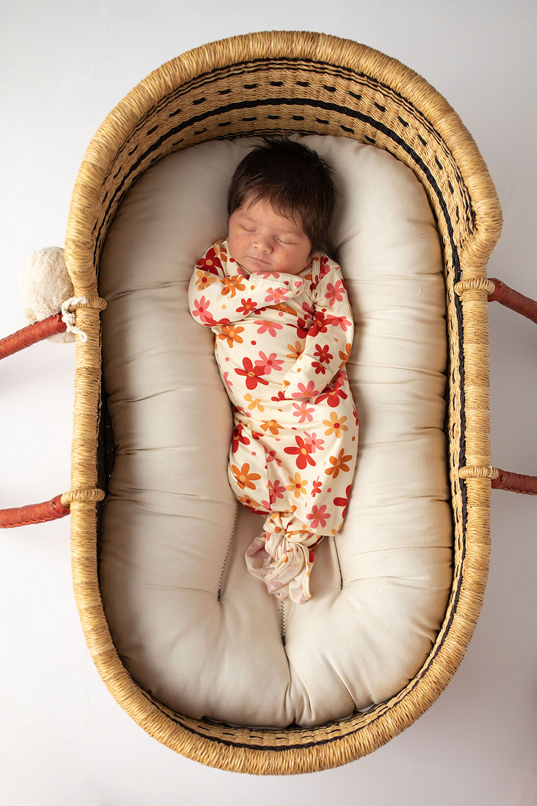 Three Little Tots Flower 70s knotted newborn baby gown is ultra soft and the perfect gift for a newborn baby. Shown in a Snuggle Me Organic in a Plum + Sparrow Moses Basket
