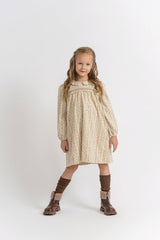 Young girl wearing a patterned dress and brown boots on a white background