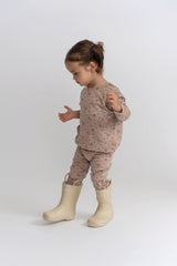 Child wearing a floral outfit with beige boots on a white background