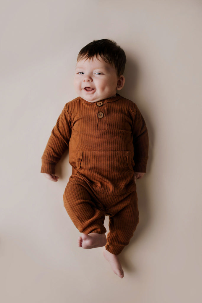 Organic cotton ribbed onesie with front buttons and leg snaps, ideal for comfort and style during any activity.