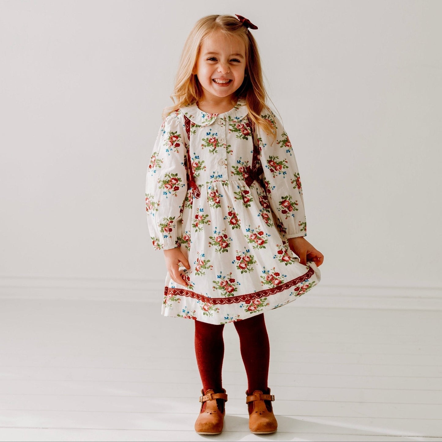 Young girl wearing a floral dress on a plain background