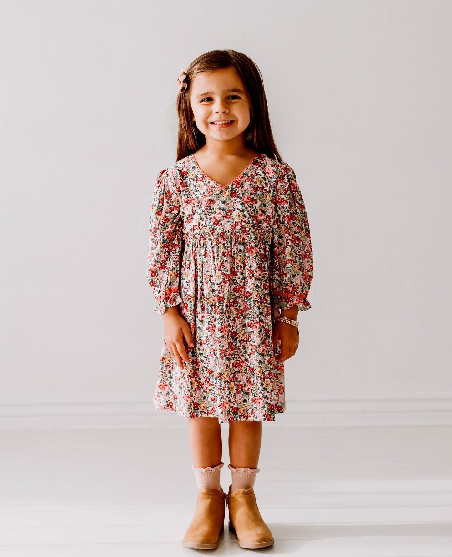 Young girl wearing a floral dress against a plain background