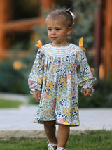 Child wearing a floral dress with ruffled sleeves outdoors