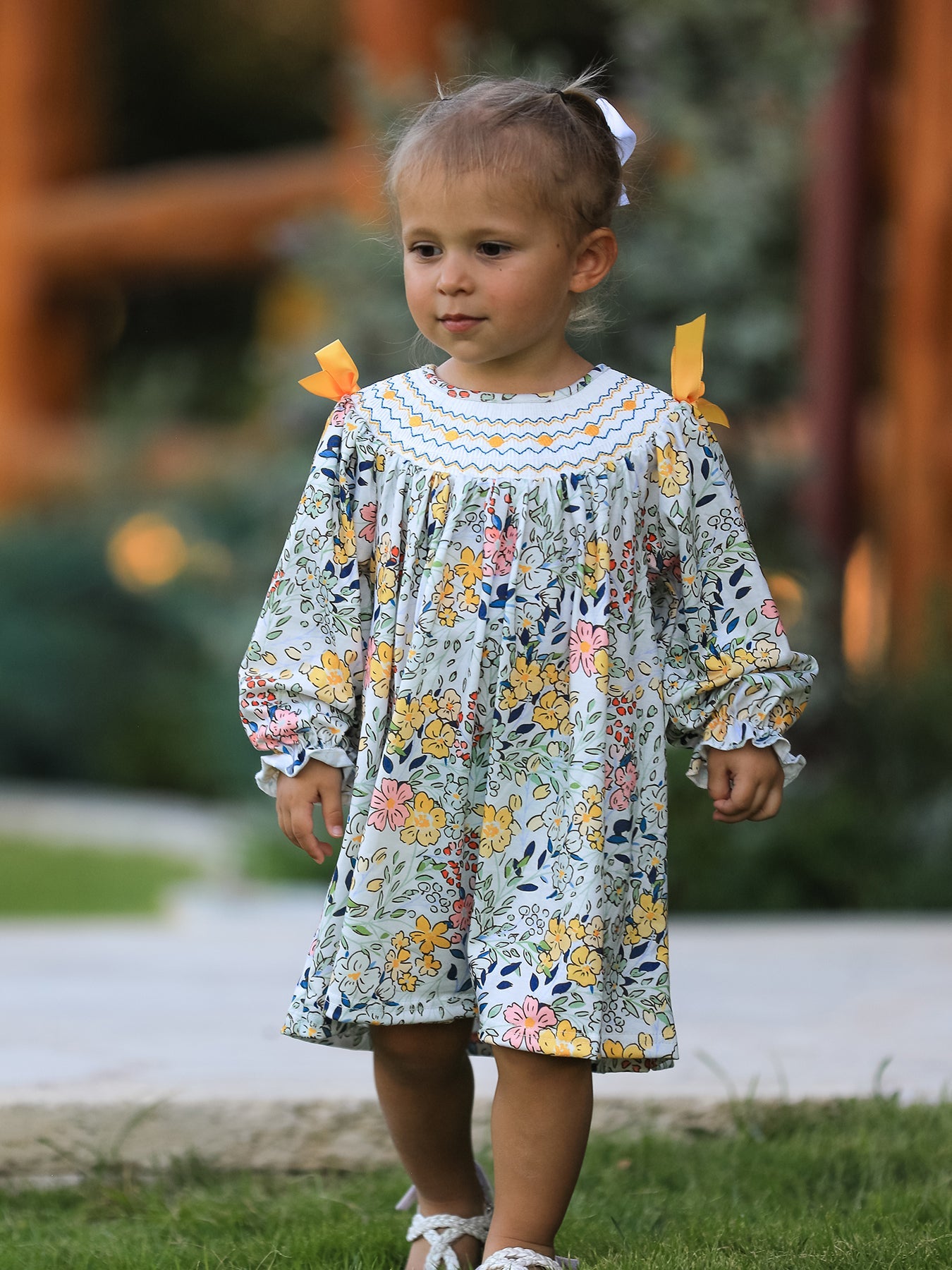 Child wearing a floral dress with ruffled sleeves outdoors