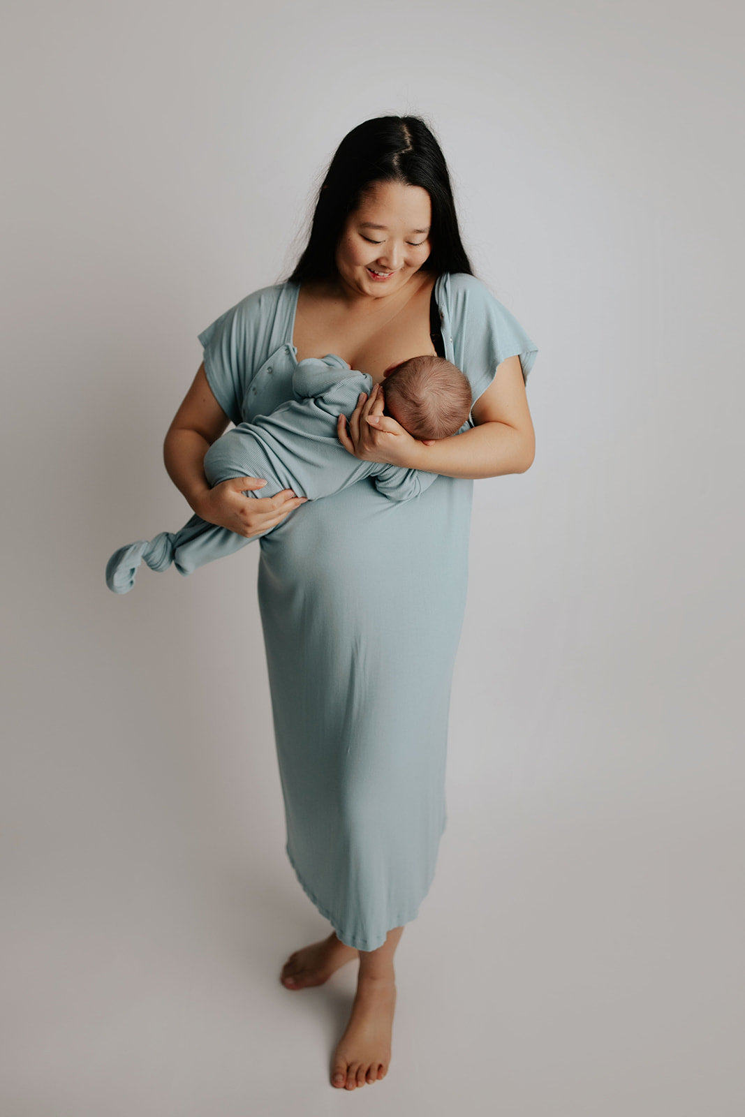 breastfeeding newborn in Three Little Tots matching blue bird labor gown and blue bird knotted baby gown