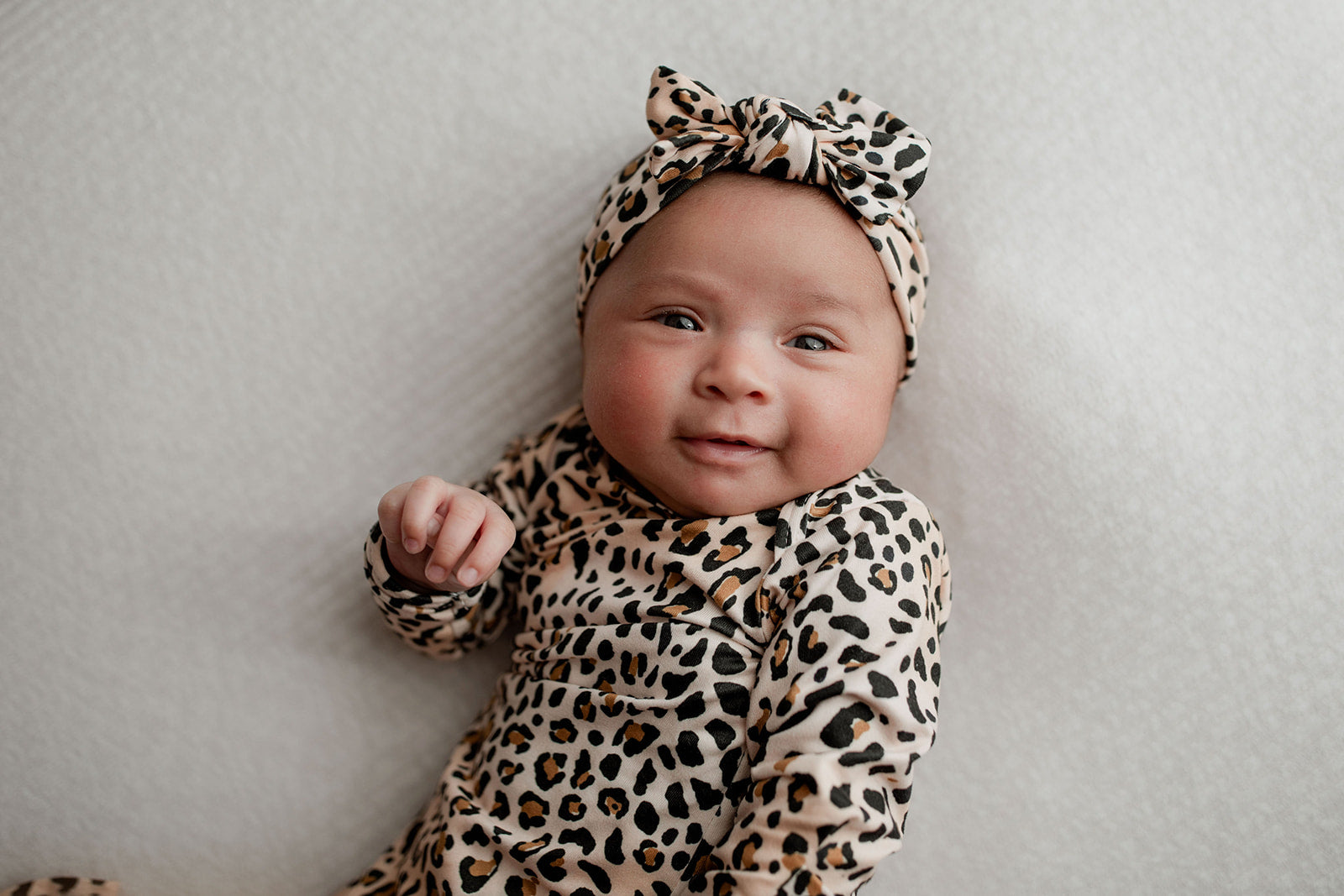 A newborn photoshoot idea with the Leopard Three Little Tots knotted baby gown with a cute bow.