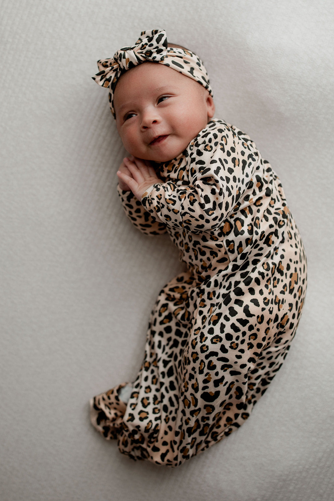A newborn photoshoot idea with the Leopard Three Little Tots knotted baby gown with a cute bow.