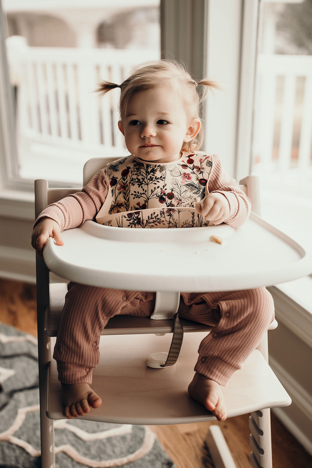 Little girl eating with a Three Little Tots floral silicone bib